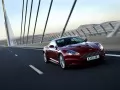 обои для рабочего стола: «Тёмно-вишнёвый Aston Martin DBS едет по мосту»